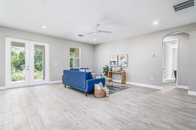 living room with french doors, ceiling fan, and light wood-type flooring