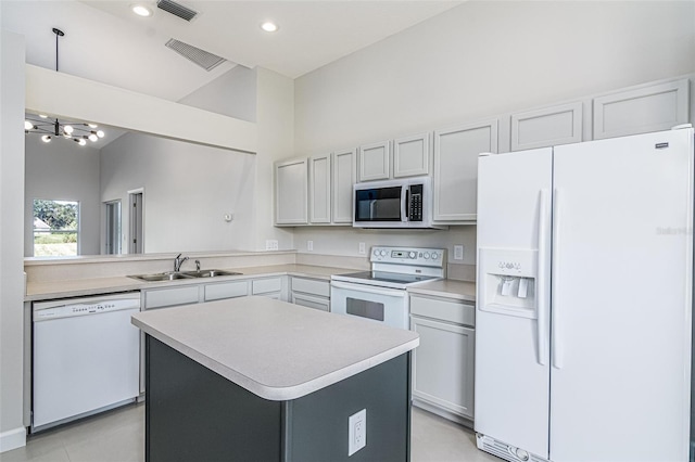 kitchen featuring white appliances, sink, a center island, white cabinets, and a notable chandelier