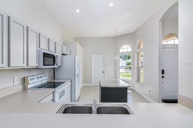 kitchen featuring white appliances, sink, kitchen peninsula, hanging light fixtures, and light tile patterned floors