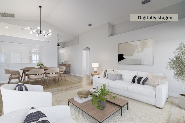 living room featuring light hardwood / wood-style floors, lofted ceiling, and a chandelier