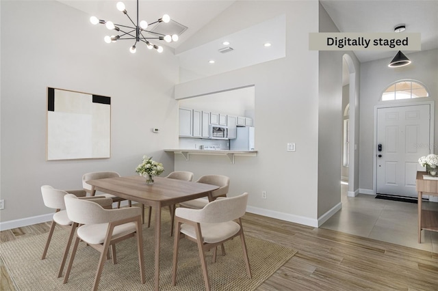 dining space with high vaulted ceiling, a chandelier, and light wood-type flooring