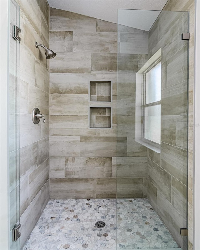 bathroom with a shower with door and vaulted ceiling