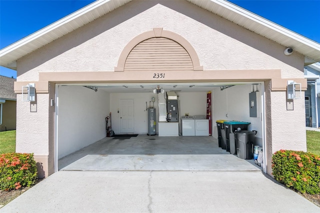 garage featuring washer and dryer, a garage door opener, heating unit, electric water heater, and electric panel