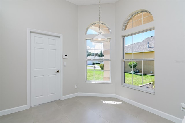 tiled empty room featuring a high ceiling and a healthy amount of sunlight