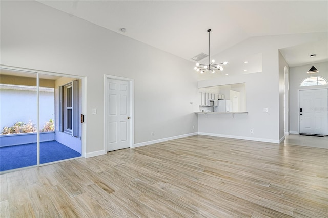 unfurnished living room with light hardwood / wood-style floors, a notable chandelier, and high vaulted ceiling