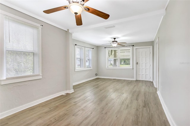 spare room featuring a healthy amount of sunlight, wood-type flooring, and ceiling fan