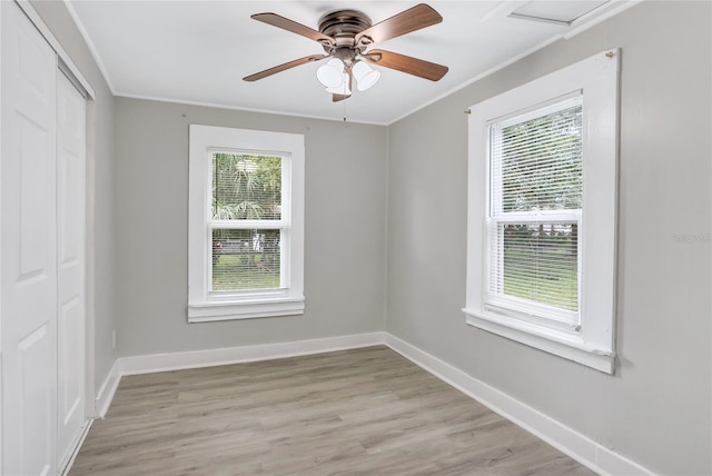 spare room featuring crown molding, light wood-type flooring, and a wealth of natural light