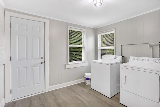 laundry area featuring ornamental molding, wooden walls, independent washer and dryer, and light hardwood / wood-style floors