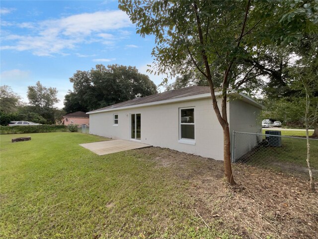 rear view of house with central air condition unit, a patio area, and a lawn