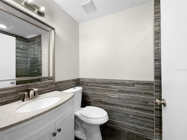 bathroom featuring vanity, toilet, tile walls, and tile patterned flooring