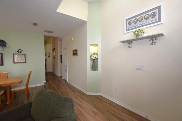 corridor featuring a textured ceiling and wood-type flooring