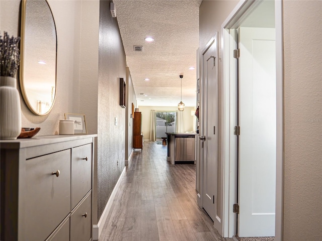 hallway with a textured ceiling and hardwood / wood-style floors