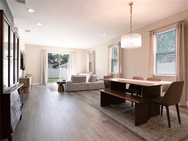 dining space featuring a textured ceiling, hardwood / wood-style flooring, and a chandelier