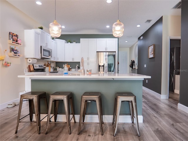 kitchen featuring white cabinetry, appliances with stainless steel finishes, pendant lighting, and a kitchen breakfast bar