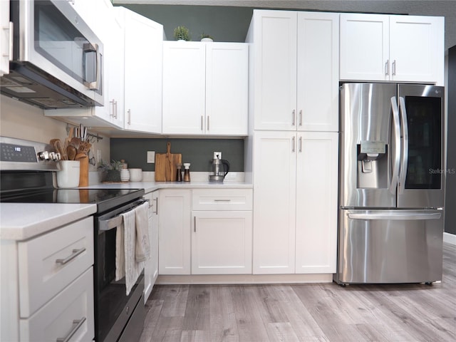 kitchen featuring appliances with stainless steel finishes, light wood-type flooring, and white cabinets