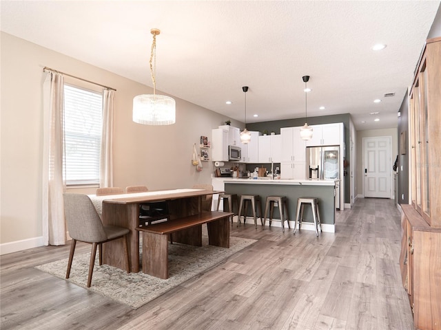 dining room with light hardwood / wood-style floors and a textured ceiling