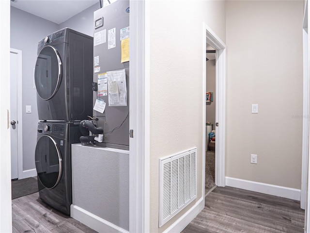 laundry room featuring hardwood / wood-style flooring and stacked washer / dryer