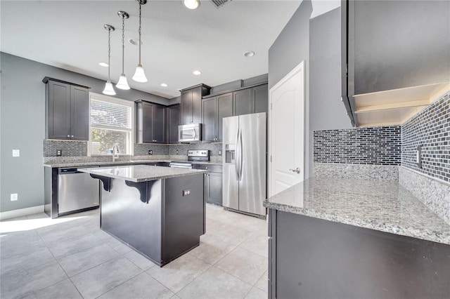 kitchen featuring tasteful backsplash, stainless steel appliances, a kitchen island, pendant lighting, and a breakfast bar