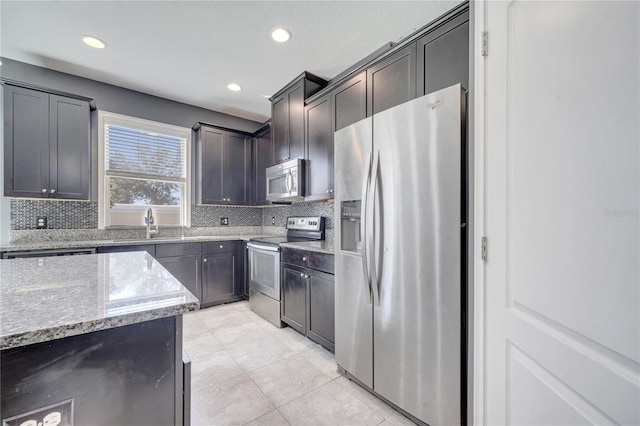 kitchen featuring stainless steel appliances, light stone counters, decorative backsplash, dark brown cabinetry, and light tile patterned floors