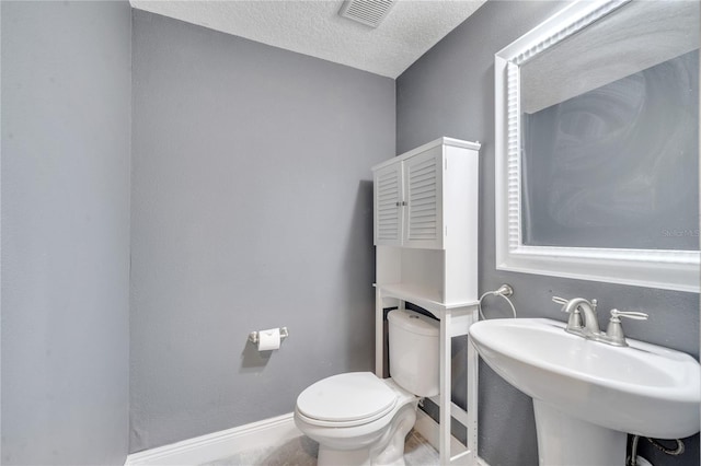 bathroom featuring a textured ceiling, toilet, and sink