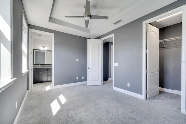 unfurnished bedroom featuring connected bathroom, light carpet, ceiling fan, and a closet