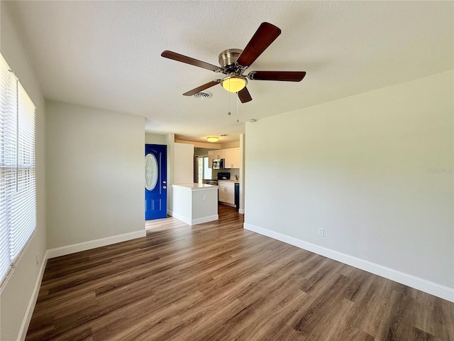 unfurnished living room featuring a textured ceiling, dark wood-type flooring, and ceiling fan