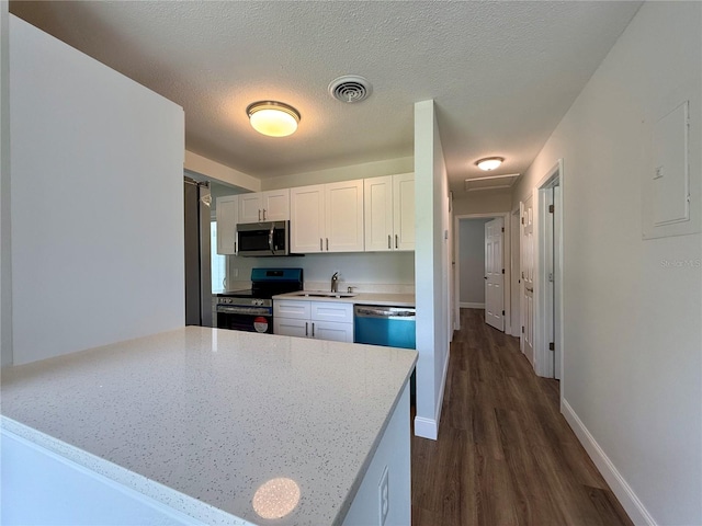 kitchen with light stone countertops, sink, stainless steel appliances, white cabinets, and dark hardwood / wood-style floors