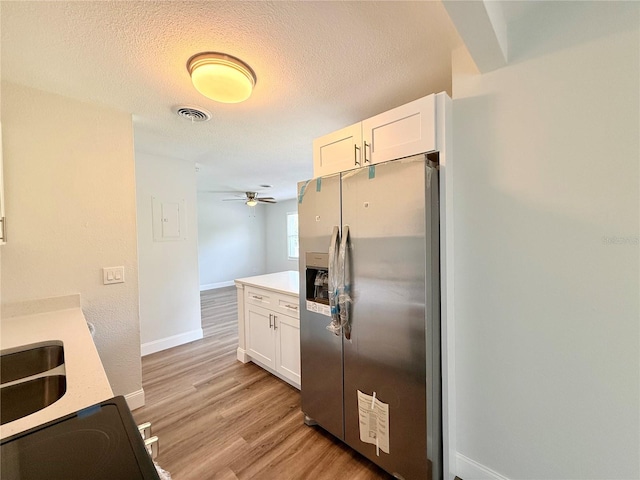 kitchen with white cabinetry, a textured ceiling, stainless steel fridge with ice dispenser, and light wood-type flooring