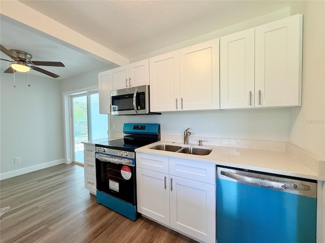 kitchen featuring wood-type flooring, sink, white cabinetry, appliances with stainless steel finishes, and a textured ceiling