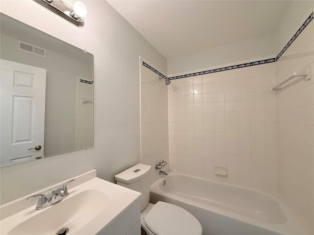 full bathroom featuring tiled shower / bath, vanity, a textured ceiling, and toilet