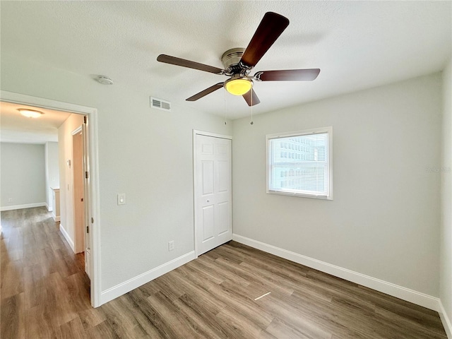 unfurnished bedroom with a closet, ceiling fan, a textured ceiling, and light hardwood / wood-style floors