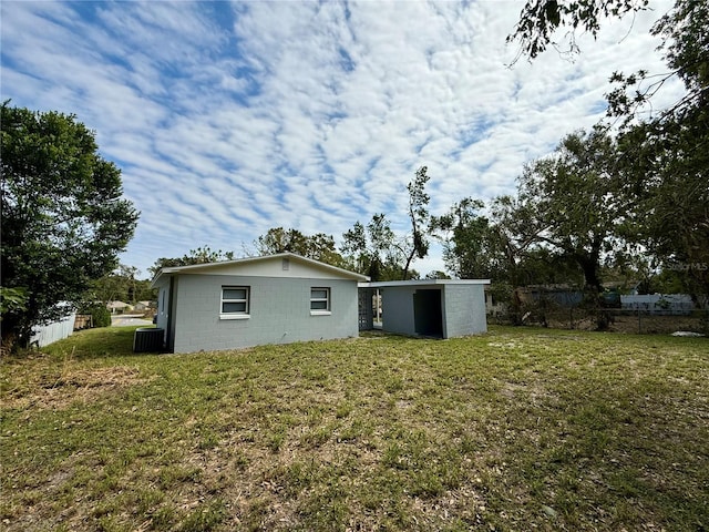 rear view of house featuring a lawn and central AC unit