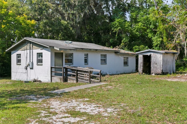 back of property with a yard and a shed