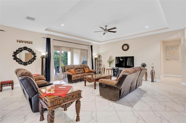 living room with ornamental molding, ceiling fan, and a raised ceiling