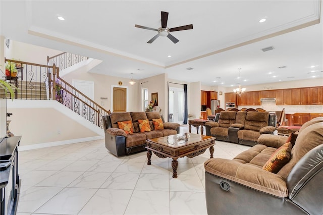 living room with a raised ceiling and ceiling fan with notable chandelier