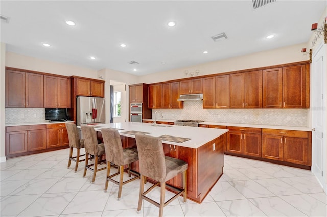 kitchen with tasteful backsplash, an island with sink, a breakfast bar area, and appliances with stainless steel finishes