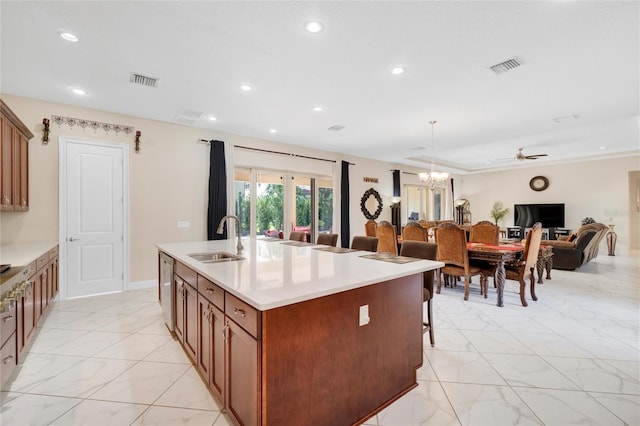 kitchen with a kitchen island with sink, sink, ceiling fan with notable chandelier, decorative light fixtures, and a kitchen breakfast bar