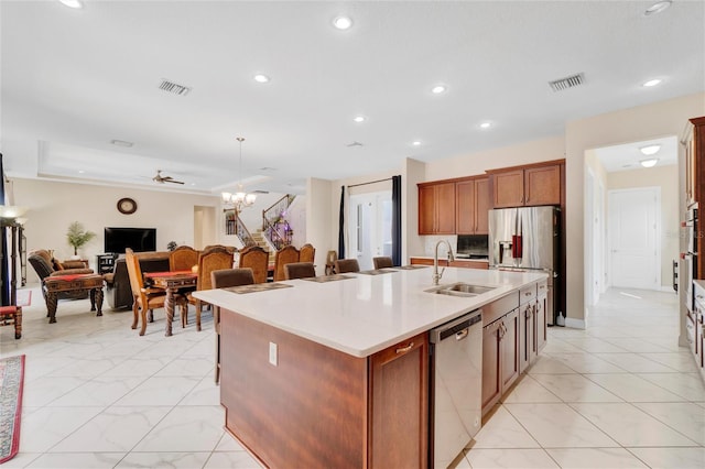 kitchen featuring pendant lighting, ceiling fan with notable chandelier, sink, an island with sink, and appliances with stainless steel finishes