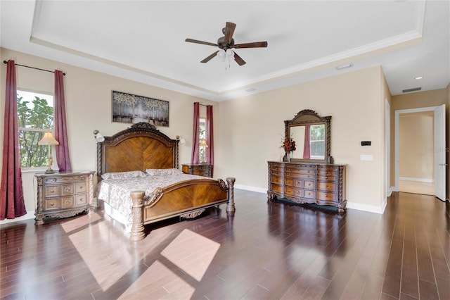 bedroom featuring ceiling fan, a tray ceiling, and dark hardwood / wood-style flooring