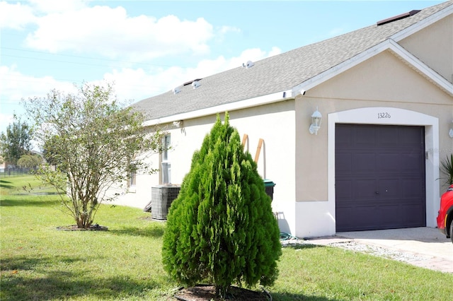 view of side of home with a yard, central AC, and a garage