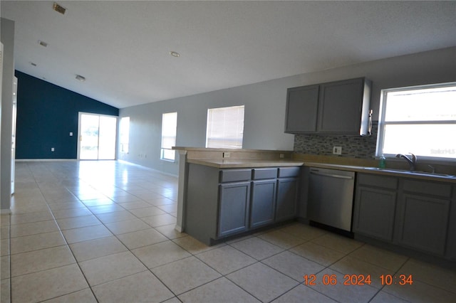 kitchen featuring dishwasher, light tile patterned floors, kitchen peninsula, and plenty of natural light