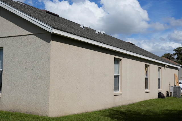 view of side of home with a lawn and central AC