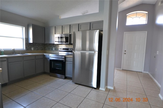 kitchen featuring lofted ceiling, stainless steel appliances, light tile patterned floors, and tasteful backsplash