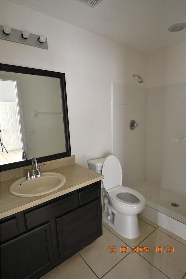 bathroom with tile patterned floors, toilet, vanity, and tiled shower