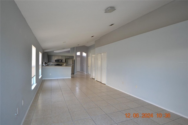 unfurnished living room featuring light tile patterned floors and lofted ceiling