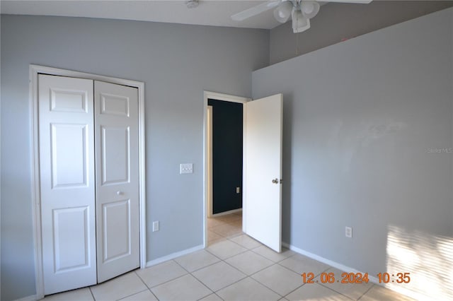 unfurnished bedroom featuring ceiling fan, a closet, light tile patterned flooring, and lofted ceiling