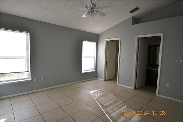 unfurnished bedroom with a textured ceiling, vaulted ceiling, and multiple windows