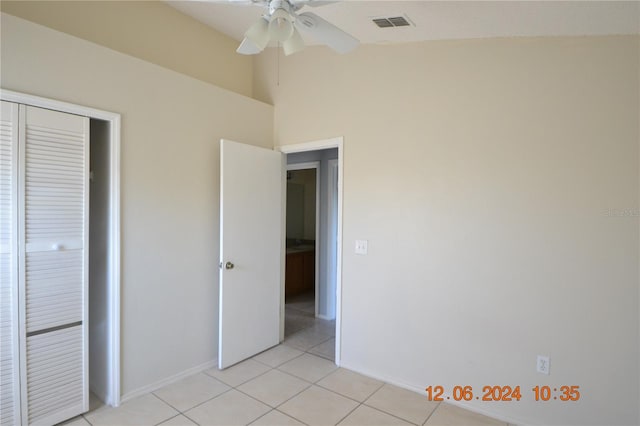 unfurnished bedroom with ceiling fan, a closet, light tile patterned floors, and lofted ceiling