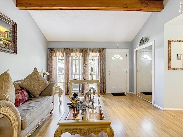 living room with lofted ceiling with beams, a textured ceiling, and light hardwood / wood-style floors