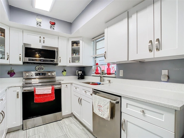 kitchen featuring stainless steel appliances, white cabinetry, light stone counters, and sink